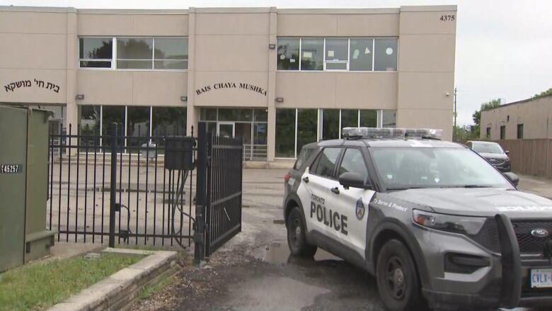 A police car is parked in front of a Jewish elementary school.