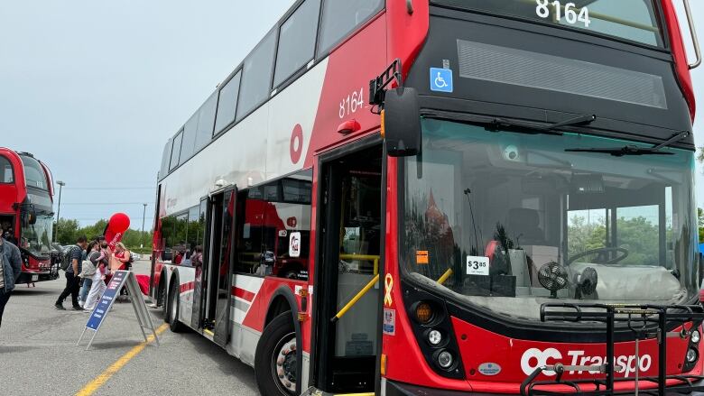 A double decker bus sits in a parking lot. 