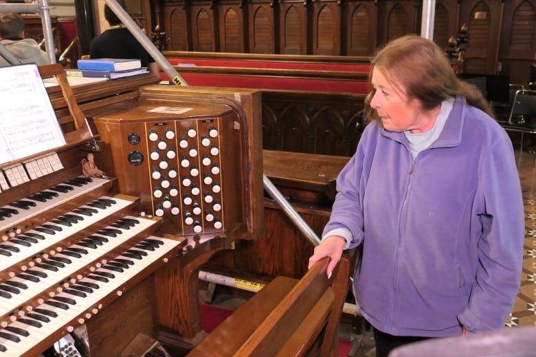 A woman standing in front of an organ.