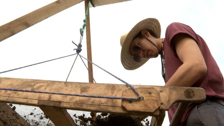 A man stands above a large tool. 