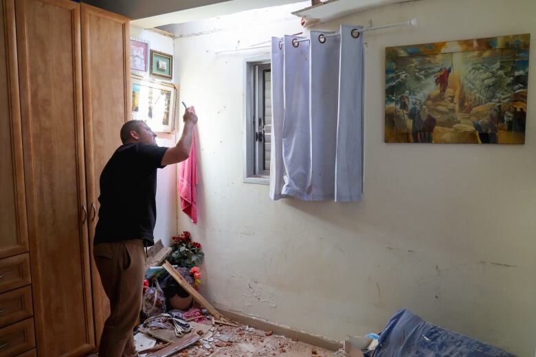 A person points their mobile phone to inspect damage to a ceiling of a room.