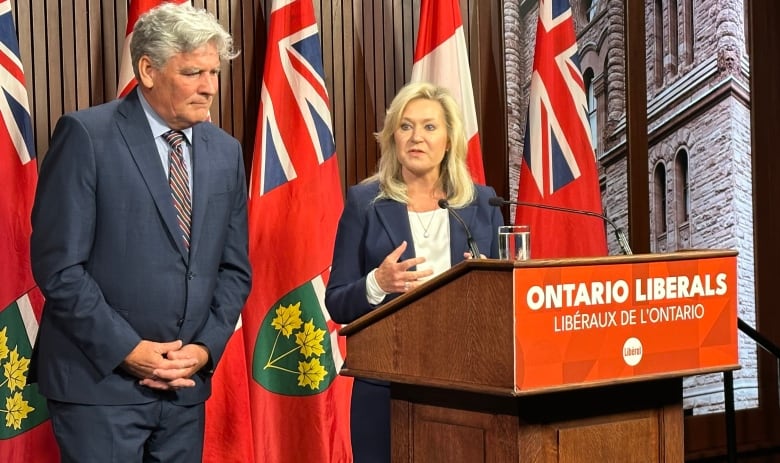 Bonnie Crombie stands a podium with a sign saying 'Ontario Liberals' as John Fraser stands to her right. 