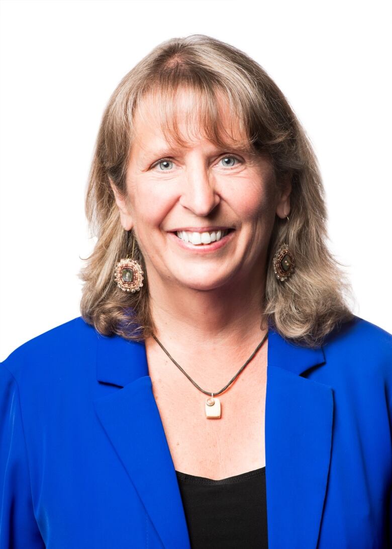 Person wearing a blue blazer looks at camera, white background