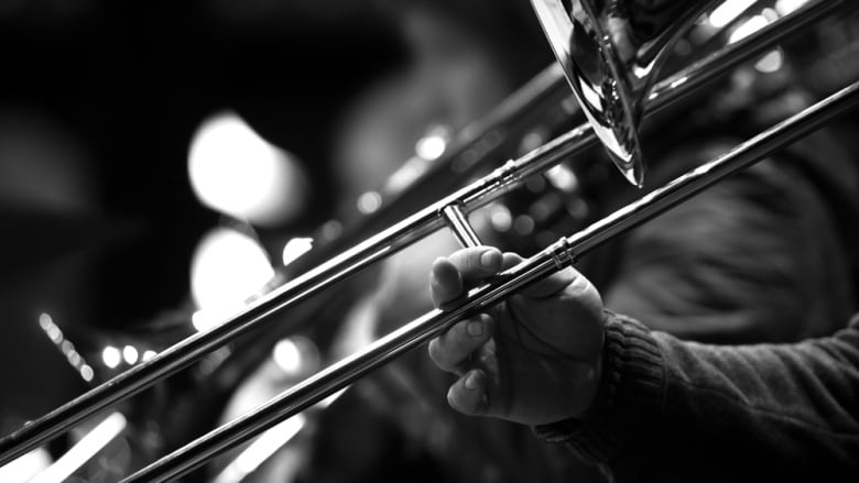 A black-and-white close-up of a person using their hand to play a trombone.