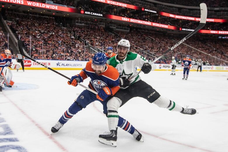 A hockey player checks another hockey player from behind.