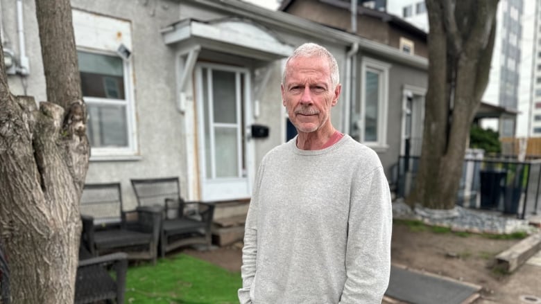 man stands in front of house