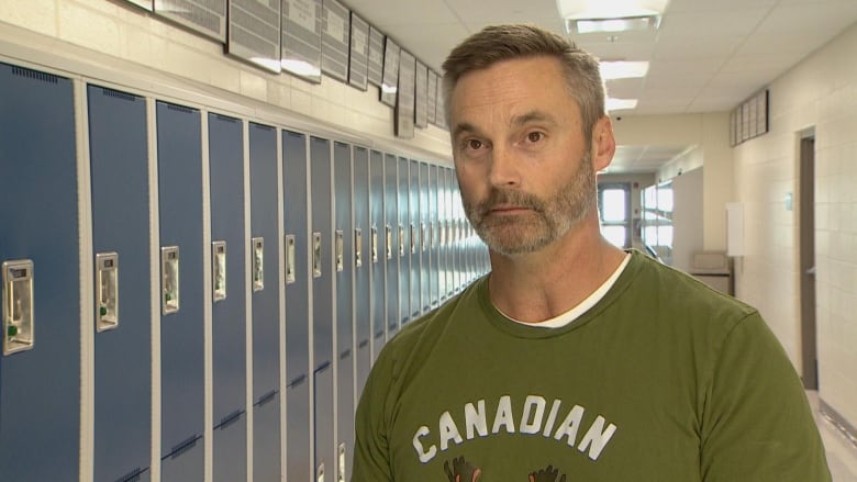 A man wears a green shirt in a hallway.