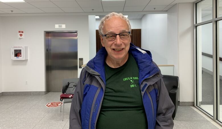 Older man standing, smiling at camera.