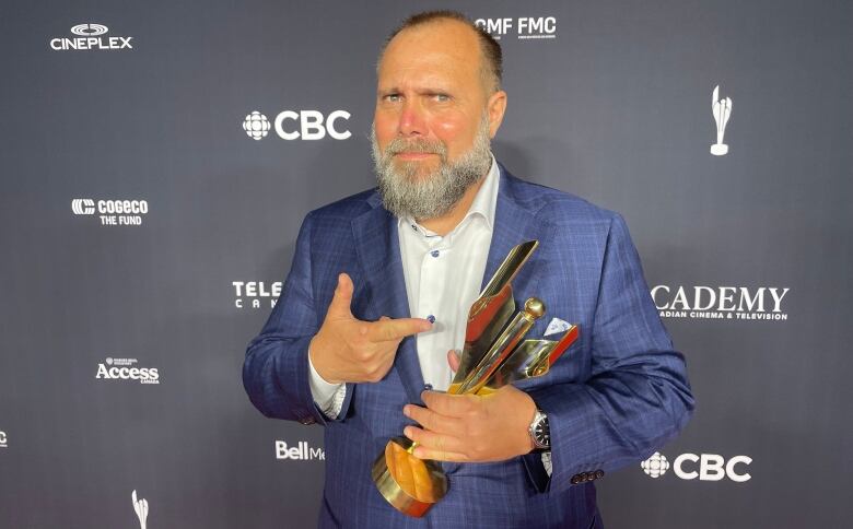 A man in a suit is pictured holding an award.