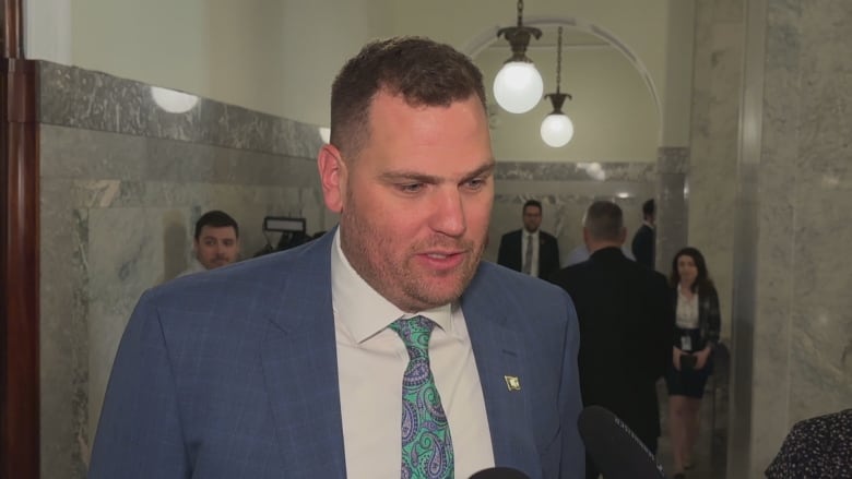 Government house leader Joseph Schow speaks to reporters in the halls of the Alberta legislature. 