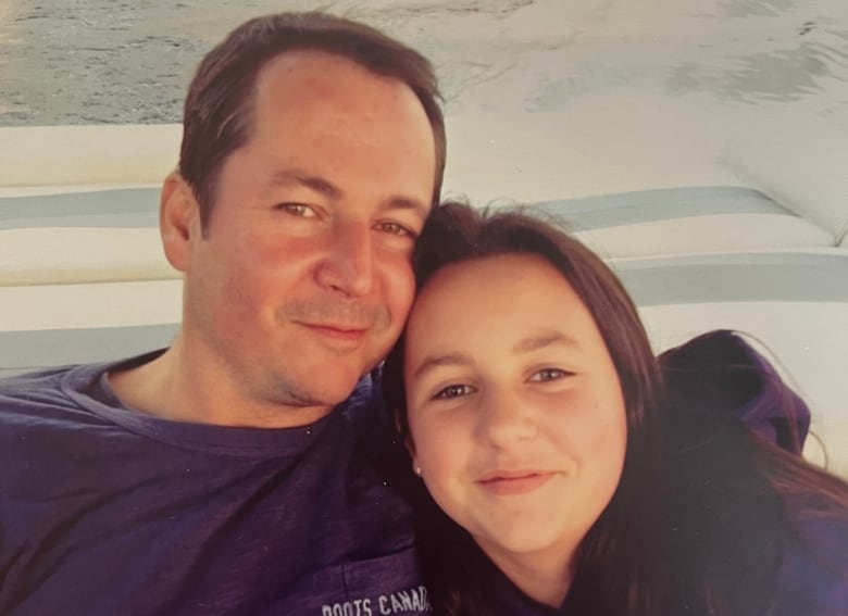 A man and young girl smile together.