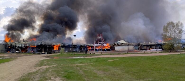 A long, low building is completely ablaze.