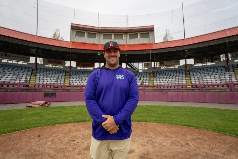 A man poses for a photo in a baseball stadium.