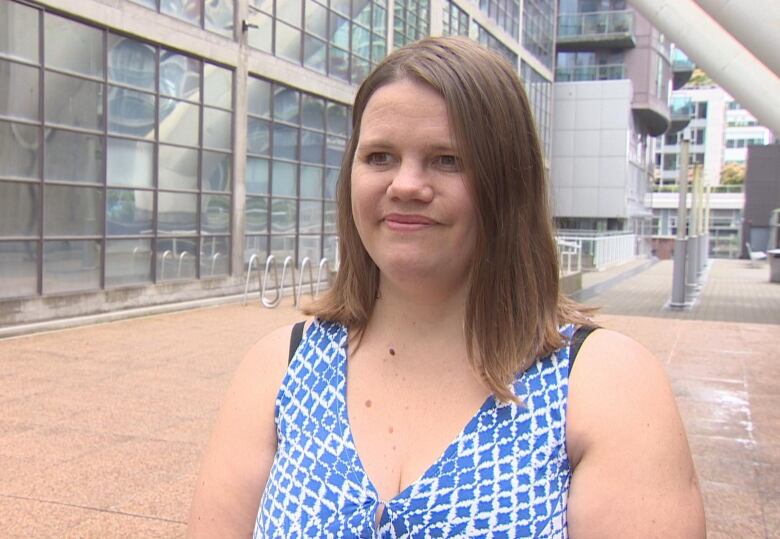 A woman stands outside of an office building.