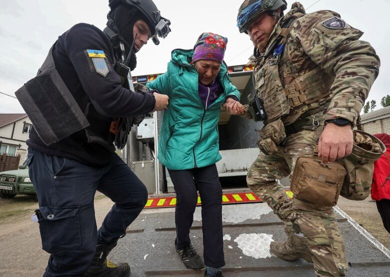 A police officer and a volunteer help a local resident from Vovchansk during their evacuation to Kharkiv due to Russian military strikes, amid Russia's attack on Ukraine, near the frontline town of Vovchansk, in Kharkiv region, Ukraine May 17 , 2024. 