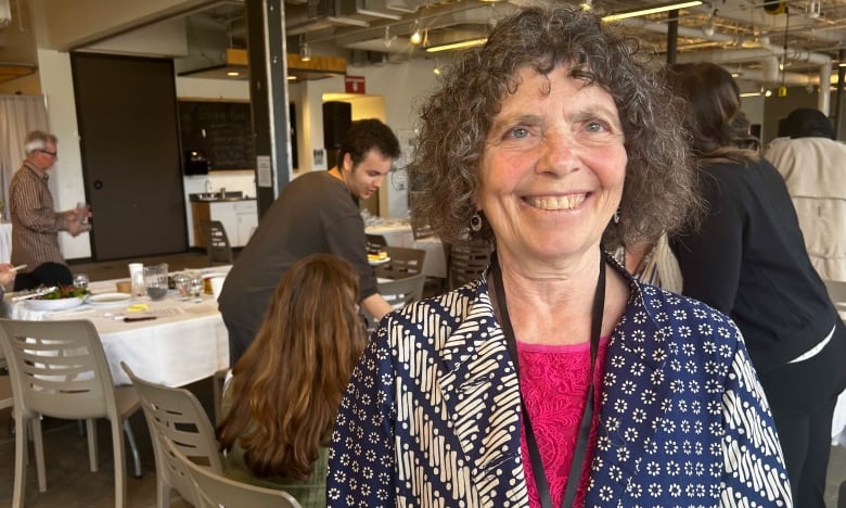 Woman with curly hair  with people sitting at tables behind her