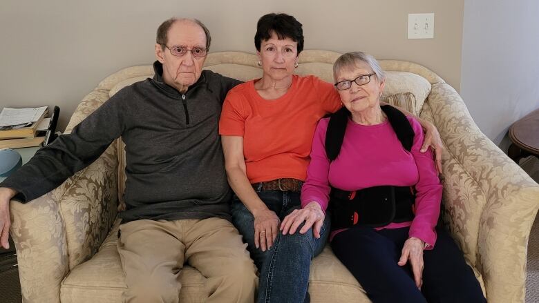 Three people sitting on a couch.