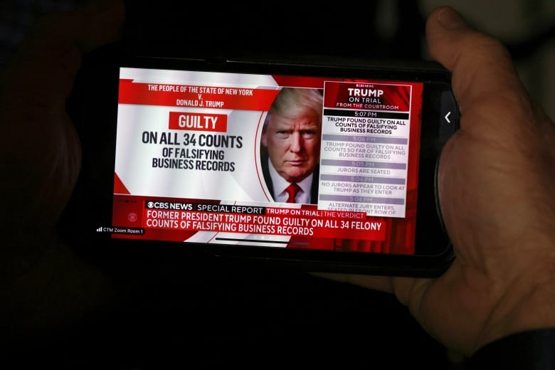 A member of the media looks at a phone screen displaying news of Donald Trump's trial verdict outcome on Thursday.