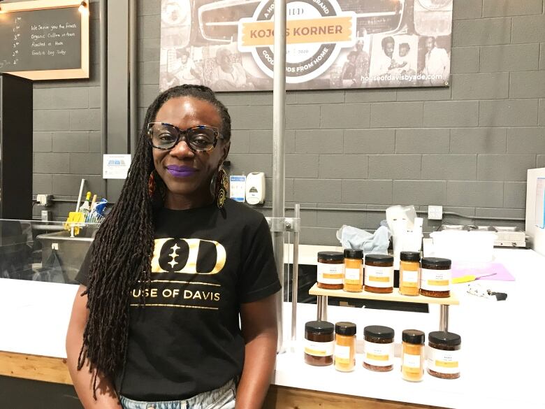 A woman stands in front of her stall full of skin care products.