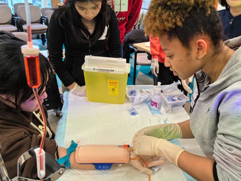 A young woman administers an injection into a model arm.