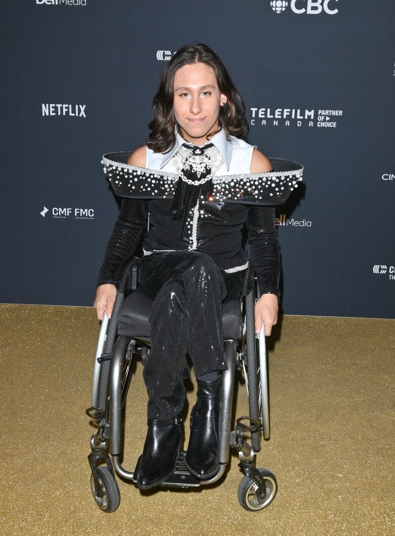 Tai Young on the Canadian Screen Awards red carpet wearing black sequin pants and a black and white top with dramatic, embellished shoulders. 