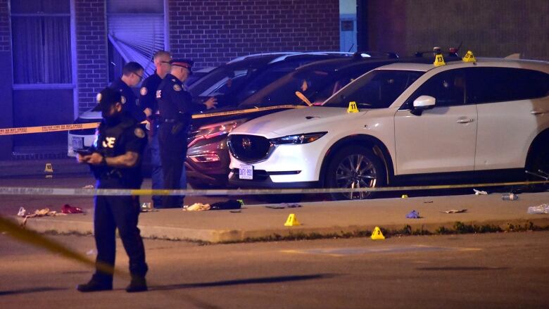 Toronto police at the scene of a fatal shooting in the parking lot of an Etobicoke high school late Sunday.