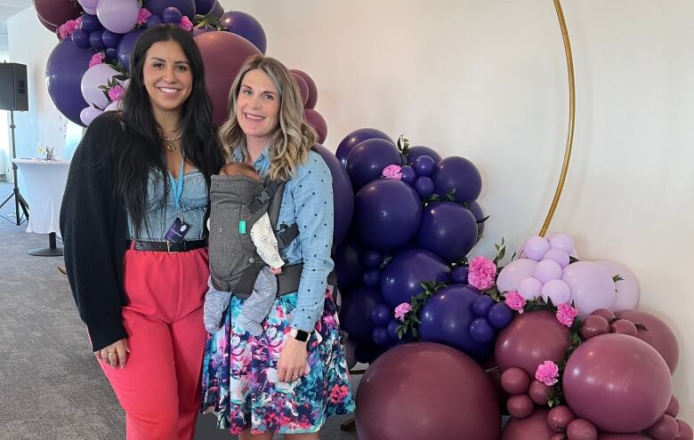 two women and a baby surrounded by balloons