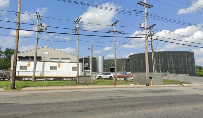 A small white building next to large round grey oil tanks