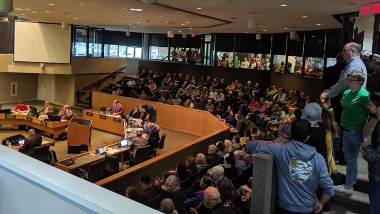 A large group of people sitting in a city council chamber.