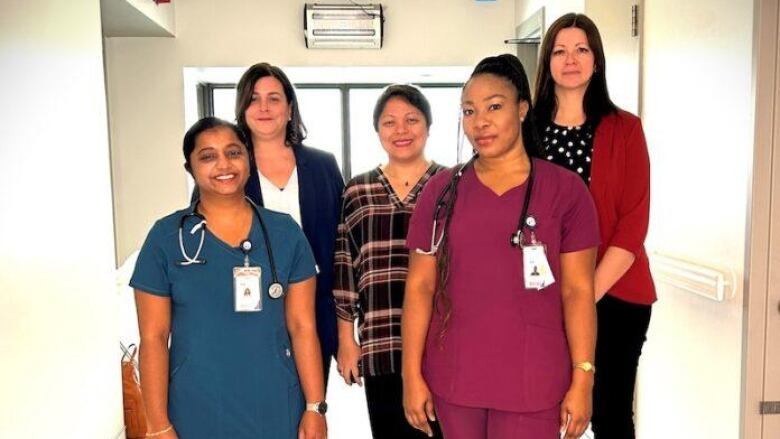 A group of women standing in a corridor wearing a hospital uniform.