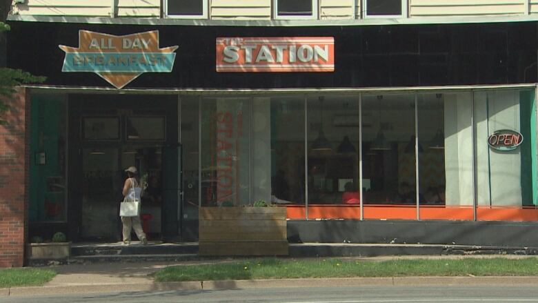 Wide shot of Robie Street Station while a woman walks through their doors.