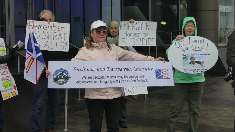 Four people holding protest signs.