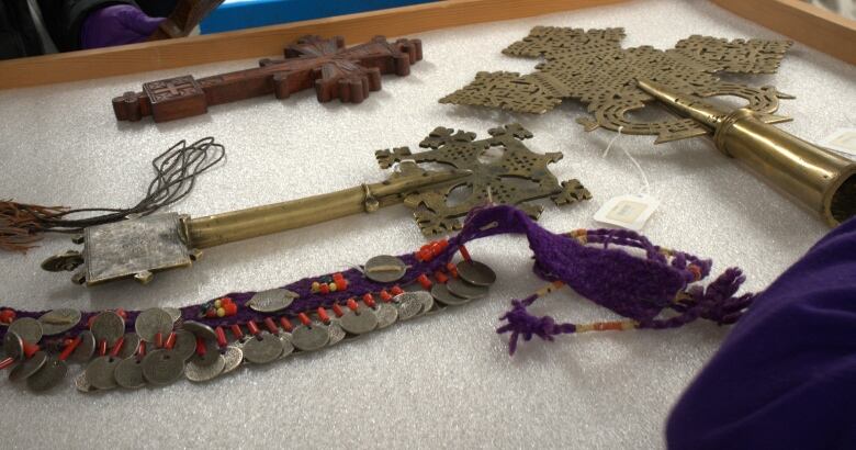 Crosses made from wood and brass rest on soft padding in a drawer. 