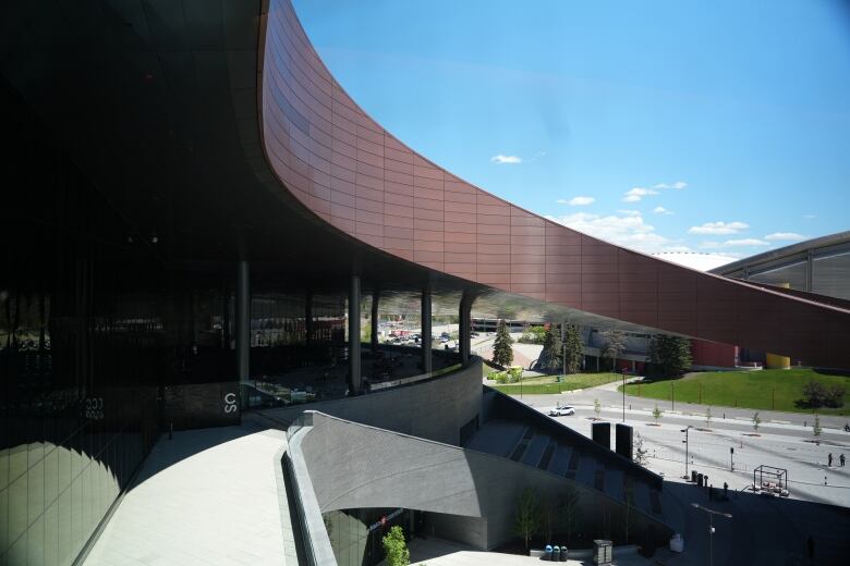 The outside of a curved building with a balcony and steps down to the ground.