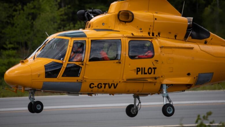 A yellow rescue helicopter takes off from a helipad.