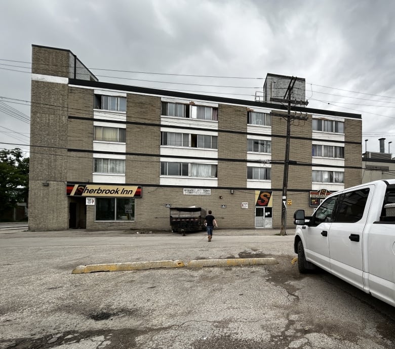 A brown brick building with 15 windows and a sign that reads, 