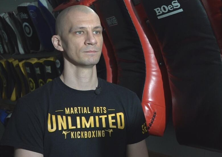 A man sits in front of martial arts training pads at a gym.