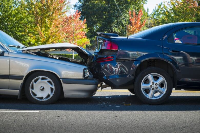 Two sedans lay smashed into each other on a street.