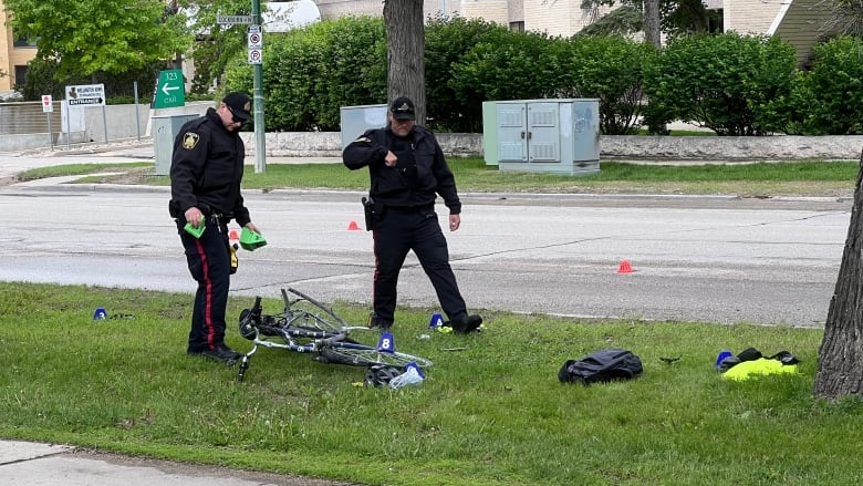 Officers put colourful markers around a damaged bicycle on a grassy boulevard.