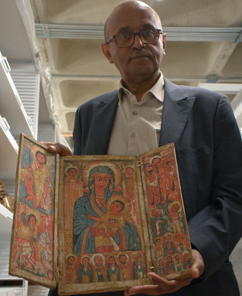 A man holds a trifold painting. 