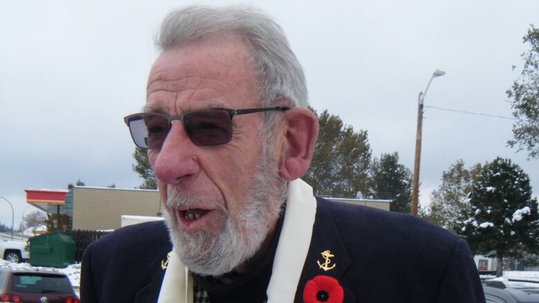 A man wears military medals and a poppy on his jacket.