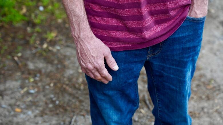 A man's torso. He's wearing a striped shirt and jeans.