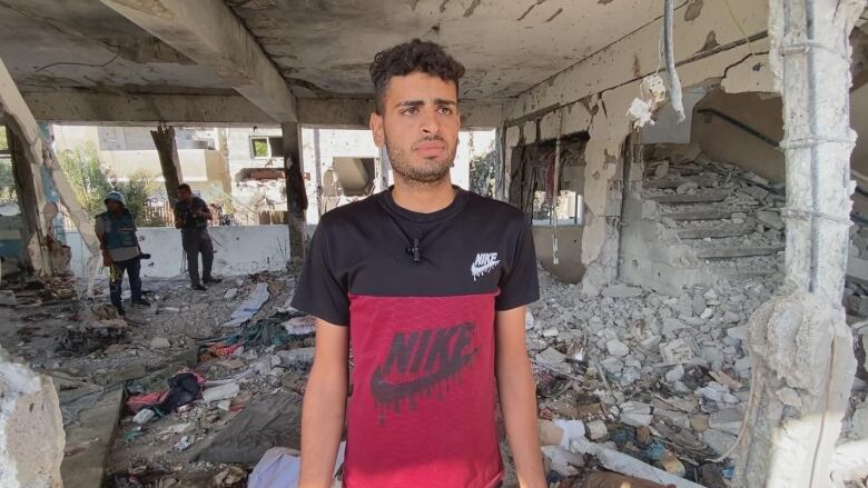 A man stands inside a building that is heavily damaged from an explosion.