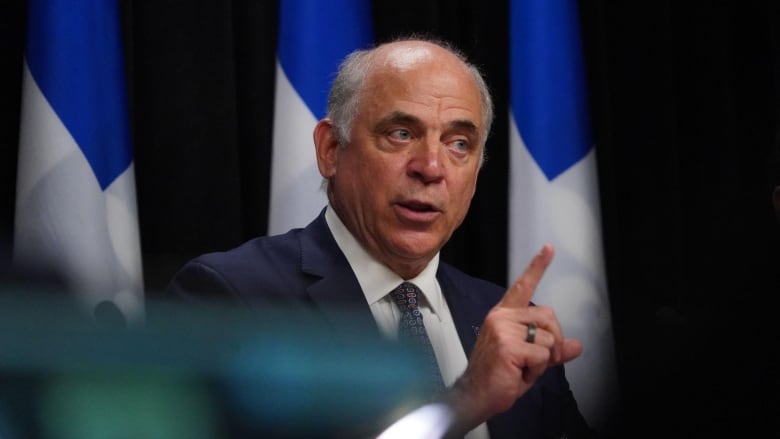  Pierre Fitzgibbon pointing while sitting in front of Quebec flag