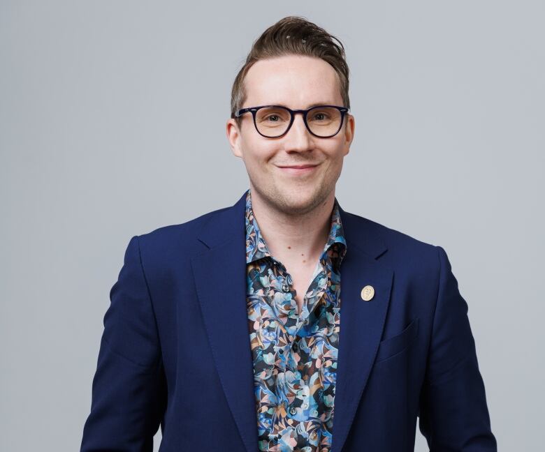 A man in a blue blazer and brightly-coloured collared shirt. 