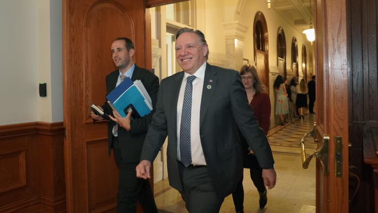 Premier Franois Legault walks ahead of a man and a woman