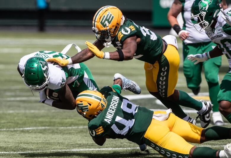 Saskatchewan Roughriders' Geronimo Allison (80) is tackled by Edmonton Elks' Nick Anderson (48) and Leon O'Neal Jr. (32) during first half CFL pre-season action in Edmonton, Alta., on Saturday May 25, 2024.