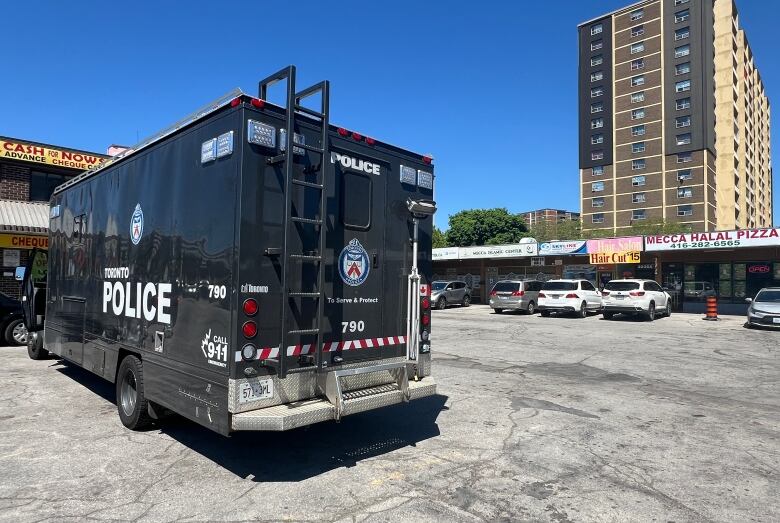 A large police vehicle sits in the parking lot of a mini-mall. 