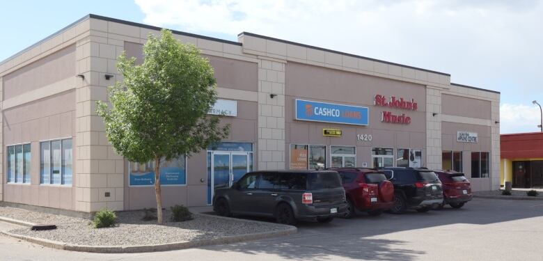 A strip mall with vehicles parked in front of it.