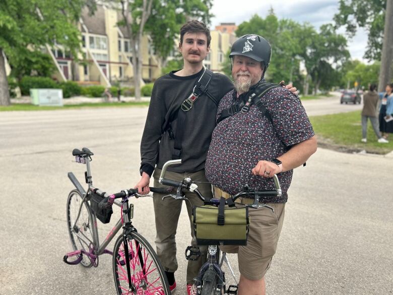 Two people standing besides some bikes.